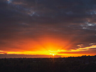 Dramatic sunset nature scene. Warm orange color sky with sun rays and flare. Stunning nature scene at dusk.