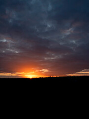 Dramatic sunset nature scene. Warm orange color sky with sun rays and flare. Stunning nature scene at dusk.