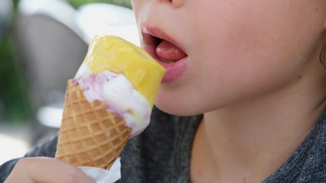 Closeup portrait of boy eating cone ice cream. Child licking ice cream.