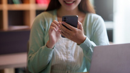 Close-up of a woman using a smartphone to work with customers via LINE messaging applications make financial transactions or play social media.