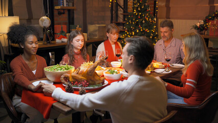 Fototapeta na wymiar A group of multi ethnic. Portrait of Caucasian and African American black family, woman have a celebration dinner in party on Merry Christmas Eve Xmas on holiday at home or house. People lifestyle.