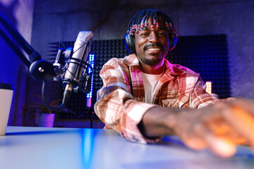 Happy young african man audio blogger broadcasting at studio