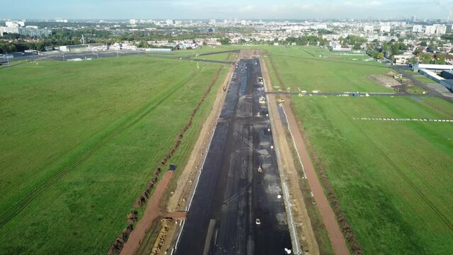 Aerial footage of Antwerp airport tarmac under construction. Building trucks on the runway while drone is flying over