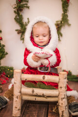 
Little cute boy dressed as Santa Claus in a room decorated for Christmas. Christmas and children