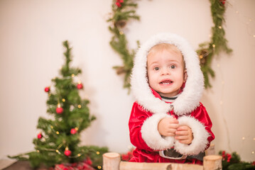 
Little cute boy dressed as Santa Claus in a room decorated for Christmas. Christmas and children