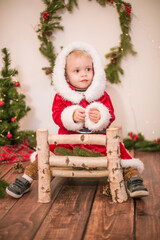 
Little cute boy dressed as Santa Claus in a room decorated for Christmas. Christmas and children