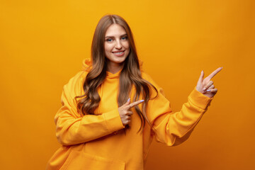 Young pretty woman pointing at copy space in studio