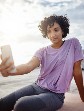 Fitness, exercise and woman taking a selfie on a phone while doing outdoor workout in the city. Healthy, young and girl athlete from puerto rico taking picture on smartphone while doing yoga on a mat