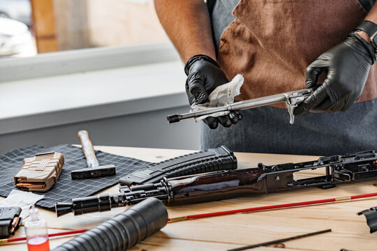 Close up of a man in apron wiping his firearm with a cloth