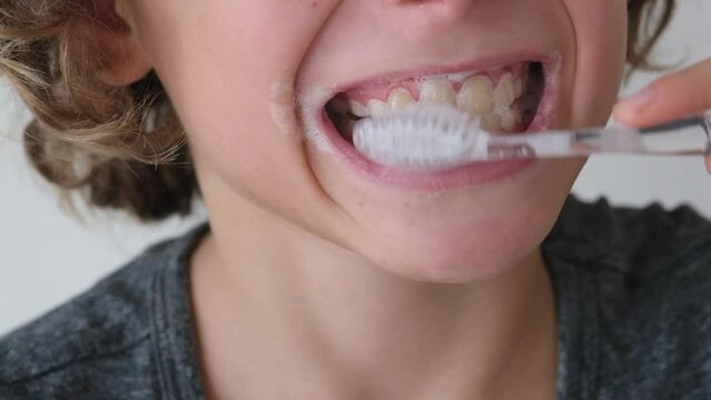 Close up child boy brushing his teeth using toothbrush and oral paste cleaning teeth.