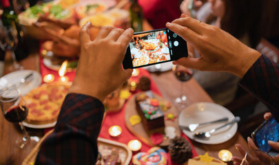 Hands taking photos by phone of Christmas party food. A celebration dinner with a turkey, wine, champagne on Merry Christmas Eve Xmas on holiday at home. People lifestyle. Thanksgiving day