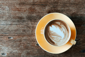 Top view of a latte art coffee on old wooden table.
