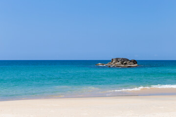 Fototapeta na wymiar Tropical beach background, clean sandy beach with blue sea background, summer outdoor day light