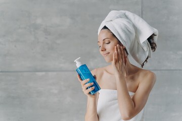 Pretty woman holds shower gel or shampoo mockup bottle, advertising cosmetics for washing, cleansing