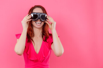 Portrait of Smiling Happy Young Caucasian Woman in Spectacles Wearing Bright Red Dress Over Pink Background.