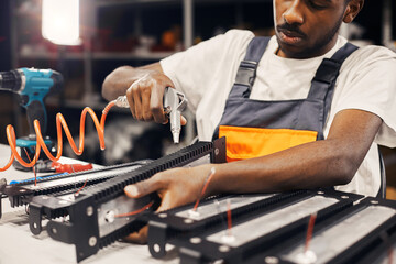 Male factory worker using electric screwdriver