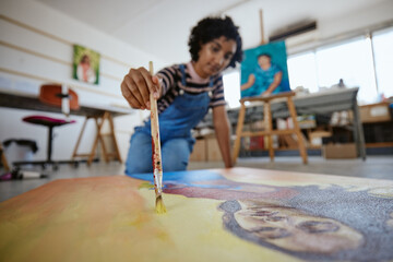 Black woman artist, canvas art painting on floor and using creativity with paintbrush to make...