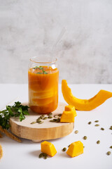 Pumpkin smoothie in a glass jar with a straw. A healthy vegan drink for breakfast.