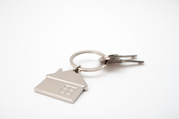 Metal key chain in the shape of a house with a metal key. Real estate concept