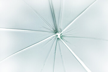 The hole in the broken and cracked glass on white background, closeup