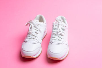 Pair of New White Sneakers Over Pink Seamless Background.