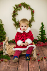 Little cute boy dressed as Santa Claus in a room decorated for Christmas. Christmas and children
