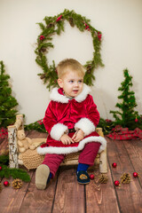 Little cute boy dressed as Santa Claus in a room decorated for Christmas. Christmas and children