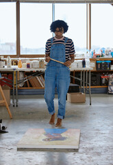 Art, creative and a woman painting on floor in studio or design school with creativity and paint...