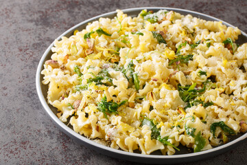 Mafalda pasta salad with arugula, roasted pistachios, parmesan cheese and lemon zest close-up on a plate on the table. horizontal