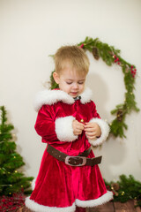 Little cute boy dressed as Santa Claus in a room decorated for Christmas. Christmas and children