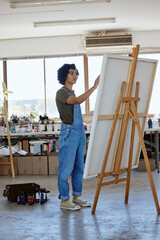 Art, creative and woman painting on canvas, learning and studying at creativity academy in a workshop. Indian designer, artist or painter with brush for picture idea at a studio or class in school © Siphosethu F/peopleimages.com