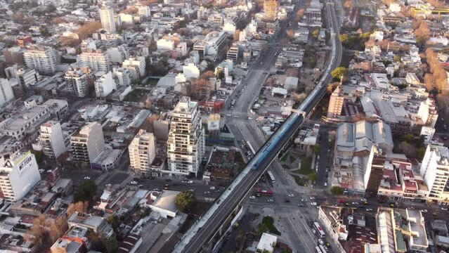 Cinematic drone flight over Cityscape of Buenos Aires and passing train on railroad above road with cars