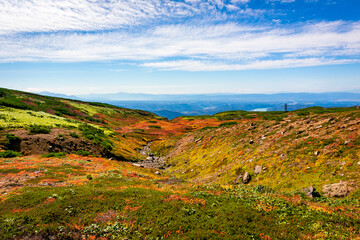 秋の北海道・大雪山の旭岳で見た、斜面に広がるカラフルな紅葉と快晴の青空