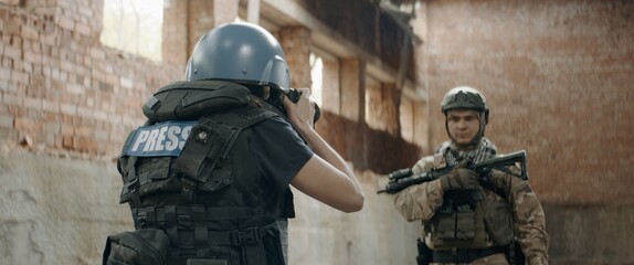 A soldier is posing for female war journalist inside destroyed building. Shot with 2x anamorphic...