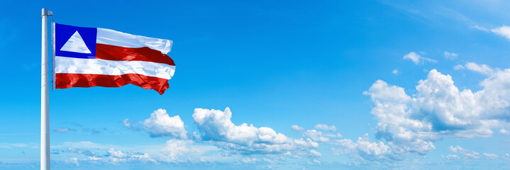 Bahia - state of Brazil, flag waving on a blue sky in beautiful clouds - Horizontal banner - obrazy, fototapety, plakaty