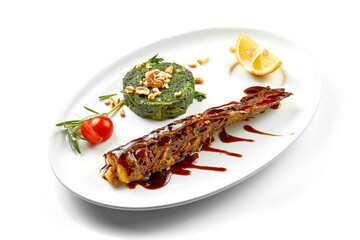 Baked fish in unagi sauce on a white plate on a white background. Close-up, selective focus.