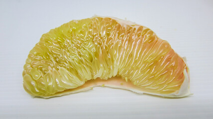 Slice of fresh pomelo or grapefruit on white background. Its pulps are clearly seen.