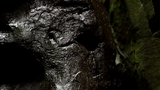 Dark look with black stones waterfall drops. Dark fantasy waterfall. Closeup of a water flowing over dark stone. Dramatic dark waterfall. 