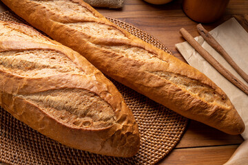 Freshly baked baguette and multigrain loaf bread on brown wooden table, Delicious baguette and multigrain bread in wooden plate on wooden table.