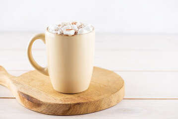 Hot cocoa drink with marshmallows on a wooden board.