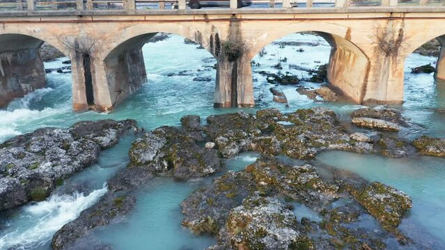Blue river flowing under an arch bridge through beautiful rocky landscape. Aerial drone view of Cijevna (Cem, Cemi) stream in Montenegro, Europe.