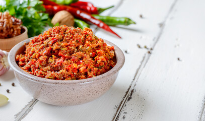 Abkhaz spicy dry adjika for meat in a bowl on a white wooden background.