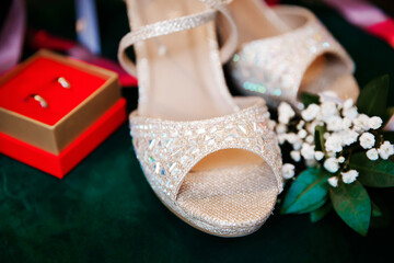Beautiful accessories of the bride..Sandals, wedding rings, flowers on an emerald chair.