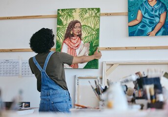 Woman artist, painter and hanging canvas on wall for exhibition to display in studio, art gallery...