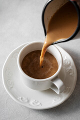 Coffee cup. Pouring milk in coffee ceramic white cup, morning hot drink. Lifestyle drink photo