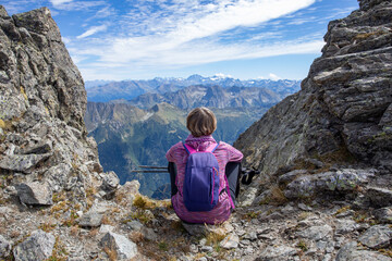 The girl is sitting on the pass against the backdrop of mountain peaks. Beautiful mountain...