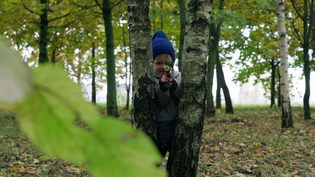 The kid shoots from the laser gun. Game in the autumn forest
