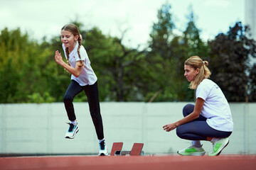 Female coach training athlete. Fit girl running on treadmill at the stadium. Concept of sport,...