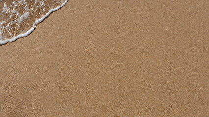 sea foam breaking on golden beach sand