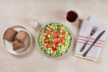 Full bowl of fresh green salad top view on a light table against a dark background on a rustic kitchen. Concept helpful and simple food